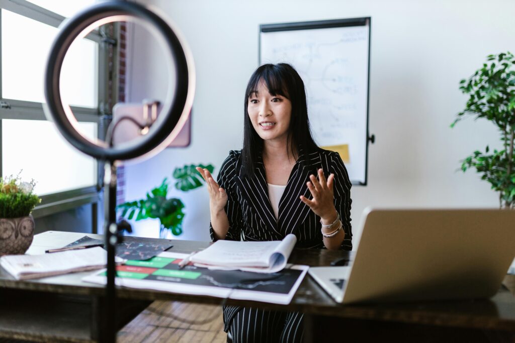 Female vlogger recording a professional video with a ring light setup, discussing finance topics.