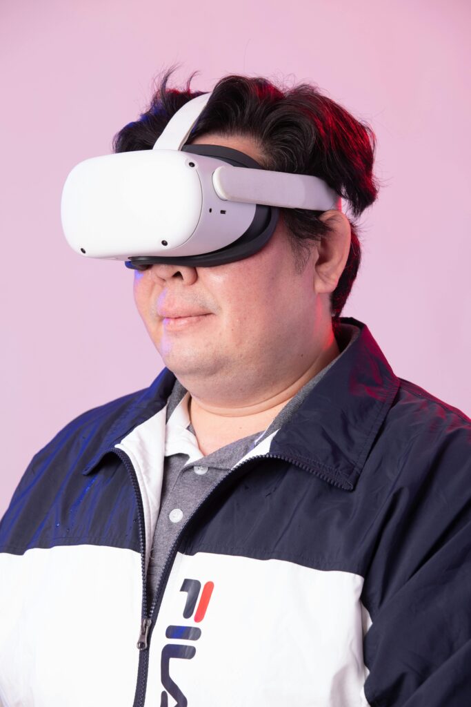 Man using VR headset immersed in virtual experience against a pink backdrop.