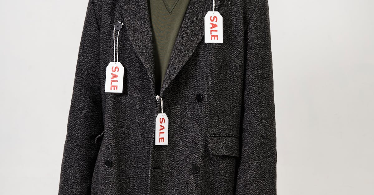 Smiling man wearing an overcoat with sale tags, holding a shopping bag during a promotional event.