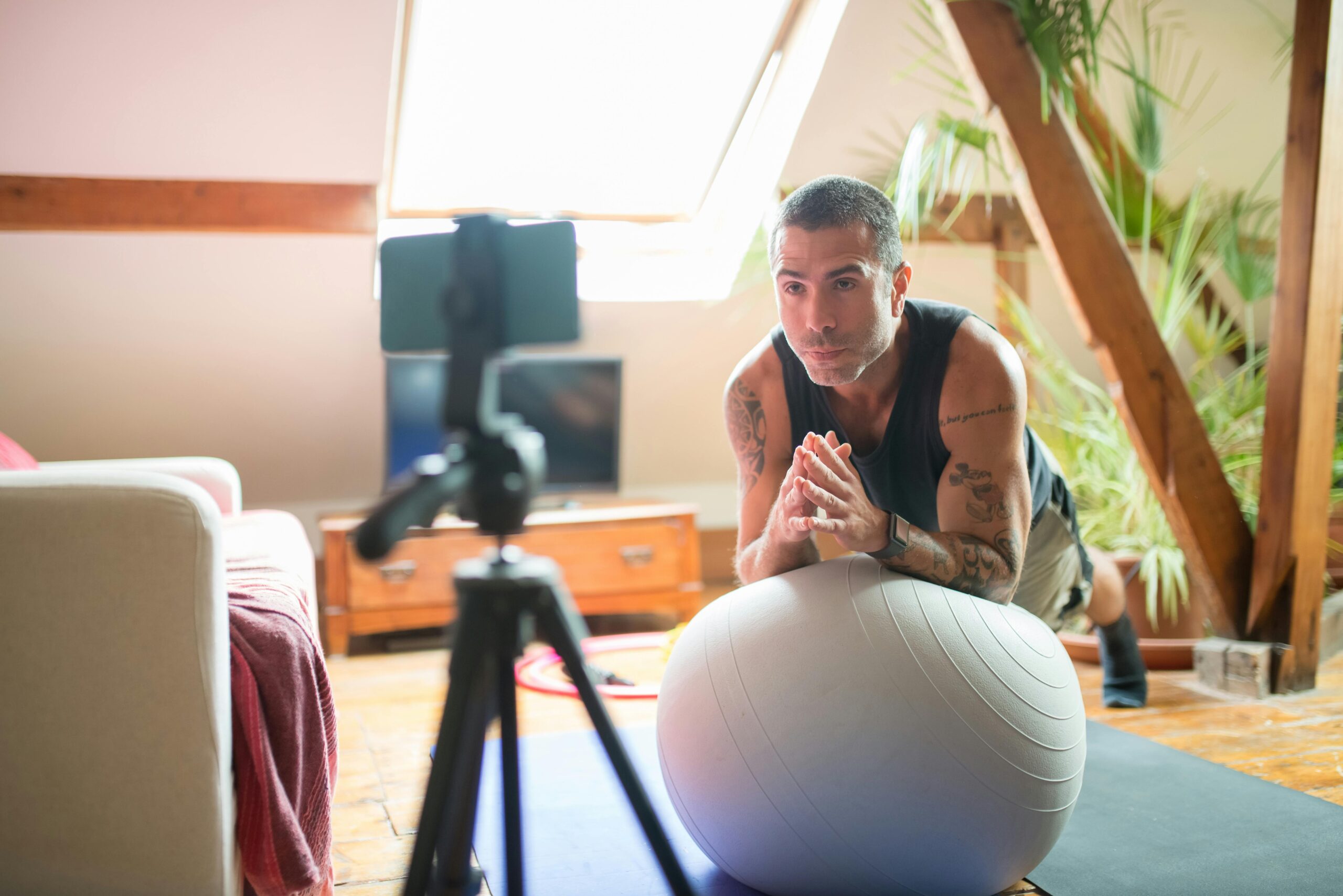 A man works out with a stability ball in a cozy home gym, recorded on a smartphone.