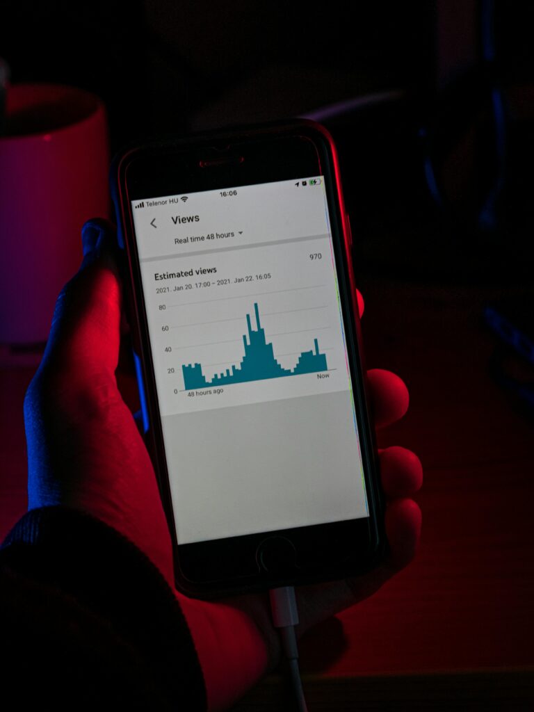Hand holding smartphone showing real-time analytics graph in a dimly lit room.