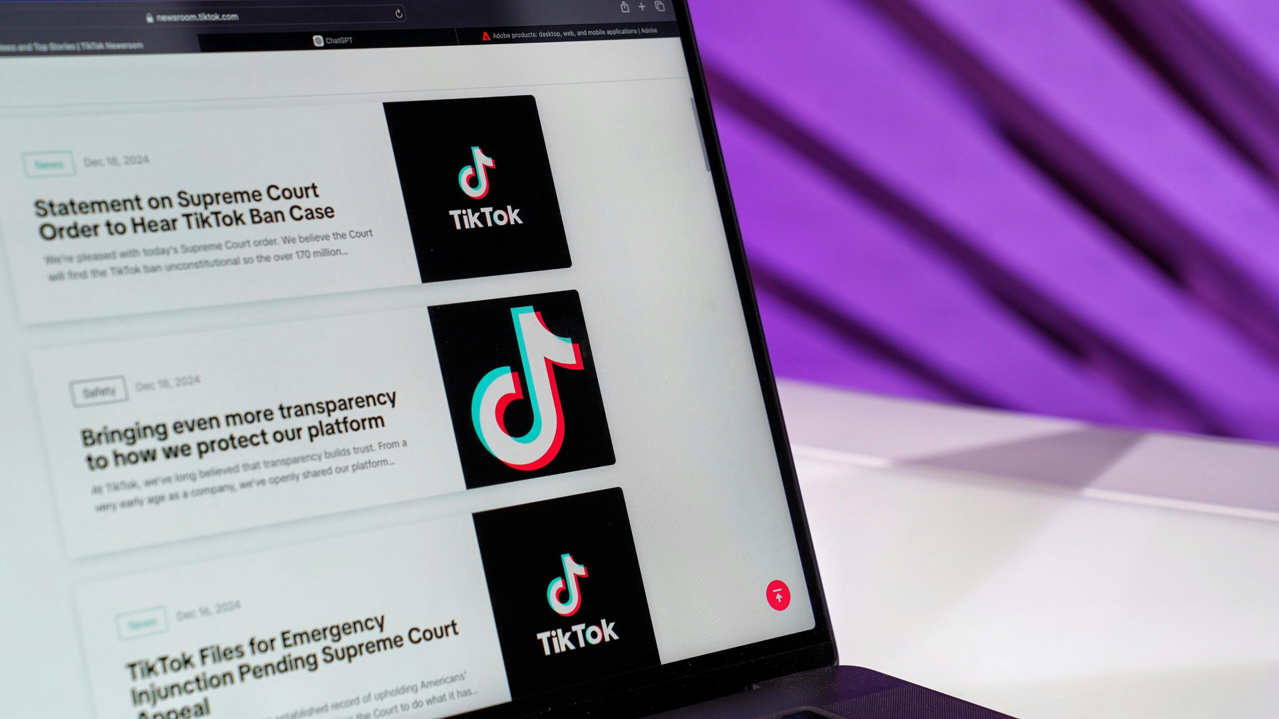Close-up of laptop screen showing TikTok news articles with a purple background.