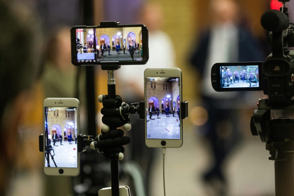 Multiple mobile phones capturing a live event at a prominent landmark in Oslo, Norway.